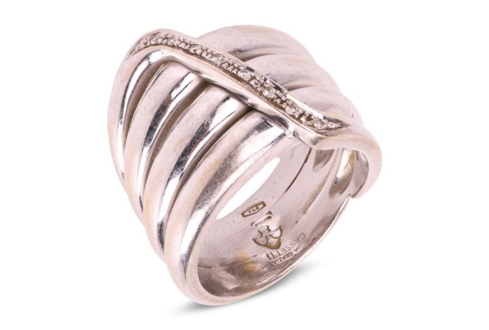A diamond-set coil ring, by Maria Grazia Cassetti, centrally embellished with an applied zig-zag motif encrusted with diamond accents, white metal signed and bearing Italian assay marks '750' and registration marks, 1.5 cm wide, size Q, 19.7 grams.