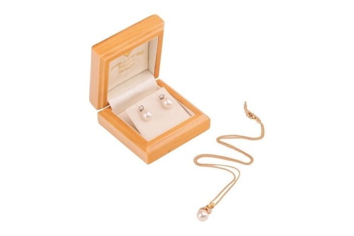 A cultured pearl and diamond necklace and a pair of cultured pearl and diamond earrings; the necklace comprising a 8.3mm cream cultured pearl detailed with a diamond-set surmount of foliate design, to a stylized bale and suspended from an 18ct fine curb-l