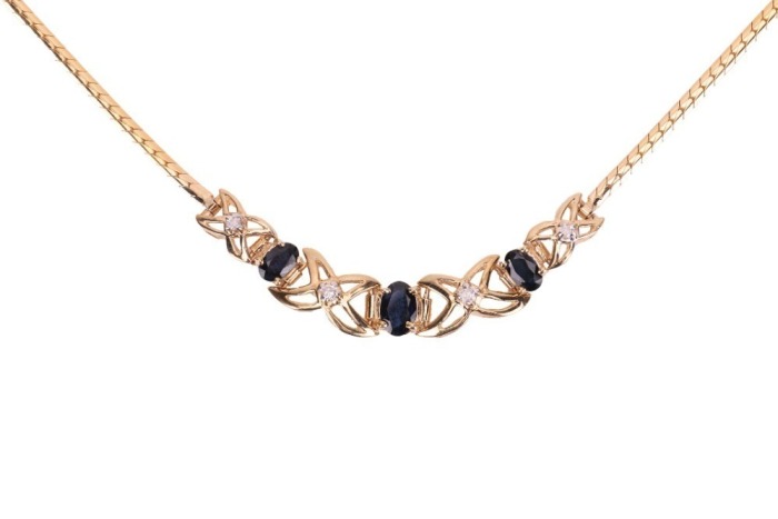 A sapphire and diamond-set necklace, set with three claw-set oval sapphires and four round brilliant diamonds, in a slightly curved mount featuring &lsquo;X&rsquo;-style links, to a flat snake-link chain to a lobster clasp, in yellow metal marked &lsquo;14K&rsquo;, measuring app