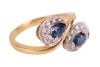 A sapphire and diamond crossover ring, consisting of two pear-shaped sapphires claw-set on white metal mounts, each encircled with diamond accents, to a tapered flat shank in yellow metal, marked as '750', ring size M&frac12;, total weight of item 4.6 grams. - 3