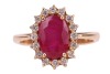 A ruby and diamond-set cluster ring, centred with an oval mixed-cut ruby measuring approximately 10.2mm x 7.2mm, surrounded by sixteen round brilliant diamonds, claw-set in a yellow metal mount marked &lsquo;750&rsquo;, size S; 5.9 grams - 2