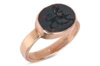 A gem-set signet ring, composed of an oval bloodstone plaque, the intaglio motif depicting a crowned lion, bezel-set in a yellow metal mount marked &lsquo;9ct&rsquo;, size N1/2; 2.8 grams