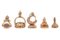 Five yellow metal seals; including a rose coloured seal with an engraved monogram to the base plate, surface testing as 14ct, 5.66 grams; a swivel triple seal, testing as 18ct; a seal set with a bloodstone plaque, topped with a fish motif, surface testing