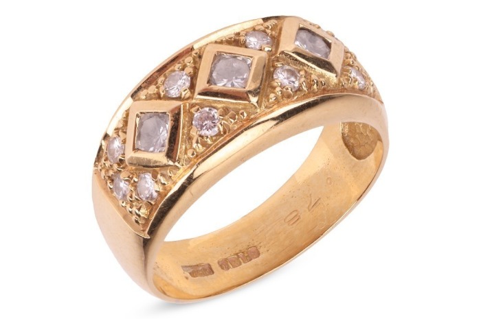 A diamond-set ring, of a chequerboard design, comprising three round brilliant-cut diamonds in square mounts, interspersed with smaller diamond accents, estimated total weight 0.38ct, in yellow metal stamped '750', size O, 5.49 grams.