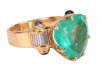 A large heart-shaped emerald dress ring, the emerald measures 13.8 x 15.0 x 8.2 mm, claw-set to the centre between trumpeted shoulders of scroll form, embellished with baguette-cut diamonds and sapphire cabochon terminals, leading to a tapering flat shank - 3