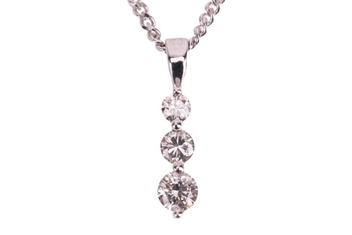 A three-stone diamond pendant, claw-set with three round brilliant diamonds of graduated sizes, with an estimated total diamond carat weight of 0.50ct, in a 9ct white gold mount, to a 9ct gold flat curb link chain, measuring approximately 46cm; 3.6 grams