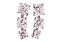 A pair of diamond-set stud earrings, each consisting of three graduated round brilliant-cut diamonds, with an estimated total weight of 1.00ct for the pair, ear post fittings, butterfly backs deficient, unmarked white metal surface testing as 18ct, 1.3 cm