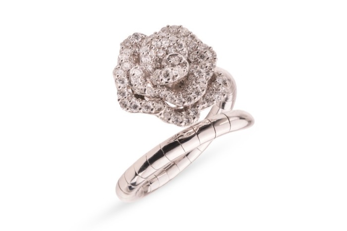 A diamond-set floral ring by Renu Oberoi, featuring a rose form, fully grain-set with round brilliant-cut diamonds, to an open white metal ring shank of bypass design, the shank with segmented detail, marked &lsquo;750&rsquo;, size L, boxed, 7.0 grams.