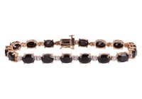 A gem-set bracelet, set with oval mixed-cut black gemstones, in a bi-colour metal mount, with integrated clasp and safety catch, marked &lsquo;14K&rsquo;; 10.5 grams