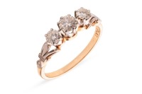 A diamond trilogy ring, claw-set with three graduated round brilliant-cut diamonds, between fleur-de-lis shoulders to D-profile shank, in bi-coloured metal stamped 'PLAT 18ct', size Q&frac12;, 3.1 grams.