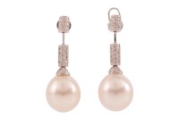 A pair of South Sea cultured pearl and diamond drop earrings, each comprising a large egg-shaped white South Sea pearl of 13.0 mm, to an articulated bar surmount, paved with round brilliant-cut diamond accents, peg and butterfly fittings, white metal mark