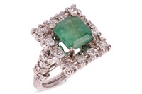 An emerald and diamond-set cluster ring, of angular form, centrally-set with a step-cut emerald measuring approximately 8.8mm x 8.4mm, within a diamond-set surround, to diamond-set shoulders, leading to a ridged white metal shank, surface tested as 9ct, s