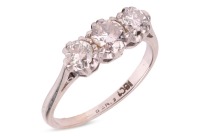 A three-stone diamond-set ring, composed of three round brilliant-cut diamonds, with an estimated total carat weight of 0.70ct, claw-set in a white metal mount, with tapered shoulders leading to a D-profile shank, marked &lsquo;18ct&rsquo;, size K1/2; 2.6 grams