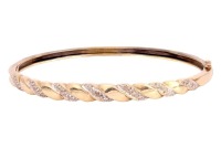 A diamond-set hinged bangle, featuring a central woven design alternating between plain yellow metal and a white metal panel grain-set with three single-cut diamonds, the bangle completed with an integral box clasp and additional safety catch, inner circu
