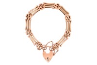 A gate-link bracelet, comprising three-row gate links completed with a heart padlock clasp, in rose coloured metal, the heart padlock marked '15ct', 15.0cm in length, 12.0 grams