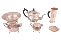 A collection of Indian (colonial style) silverware including an ebony handled tall cup, teapot, fruit bowl, ashtray, heavy gravy boat and a silver-plated spherical cream jug. 53.00 ozt/ 1651.5 grams weighable.