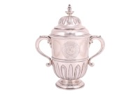 A George I Britannia standard silver loving cup and cover, London 1718, William Fawdrey bearing "Leopard's Erased" mark, the ogee moulded cover with tiered finial above a body of stiff cut card plantain leaves and lappets, and engraved with quartered armo