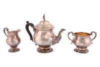 A heavy-gauge silver three-piece teaset, London 1907 by Holland Aldwinckle & Slater of baluster form with rococo decoration and flame finials, 56.17 ozt /1747 grams/ combined gross weight. 27 cm wide the teapot.