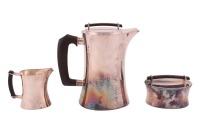 A three piece silver coffee set by Karl Karlsson; the set comprising a coffee pot, sugar basin and cream jug was designed by Einar Telander and made by Karlsson. Of hammered waisted cylindrical design, the wooden handles are anecdotally made from salvage 